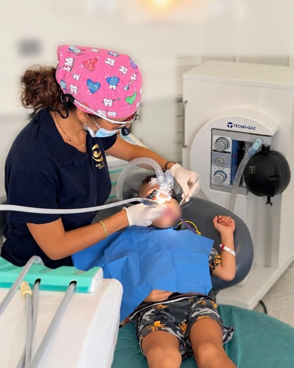 Una cura in sedazione cosciente: il bambino respira il protossido d'azoto dalla mascherina sul naso, accanto all'apparecchiatura per la sedazione